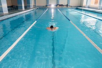 A young athlete trains and prepares for swimming competitions in the pool. Healthy lifestyle.