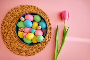 Colorful easter eggs in bowl, pink background