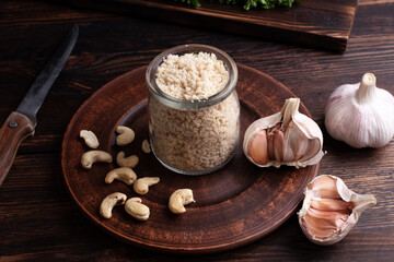 Healthy vegetarian parmesan cheese made from ground cashew nuts in a jar on a wooden background, rustic style.