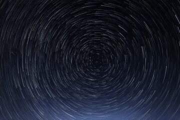 Stellar trails, the rotation of bright stars at night around the Polar Star against a blue sky and...