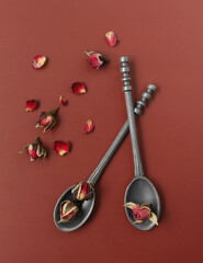 tea rose flowers in a tin spoon on a red background