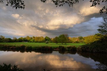 Stormy skies as the sun sets over the River Wey and meadows in Godalming, Surrey, UK
