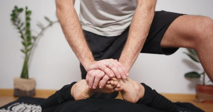 Mixed race latin woman having massage at home. Bearded man making yoga thai massage trigger point work shiatsu physical therapy fascia release