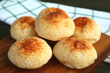 Closeup Heap of Homemade Brazilian Cheese Breads Called Pao de Queijo on Wooden Breadboard	