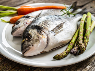 Fresh dorada and vegetables on wooden background
