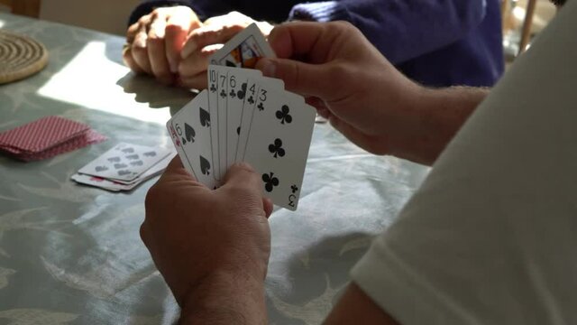 Close up footage of two men playing a game of cards at a kitchen table. Home setting playing a game of cards for fun. Real time 4k footage of card game
