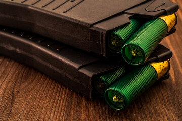 Two magazines with cartridges 12 gauge lies on each other on the wooden table. Close up view