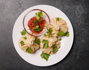 khinkali with tomato sauce, herbs on a dark ,  top view, dumplings