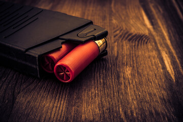Magazine with red cartridges 12 gauge on the wooden table. Close up view