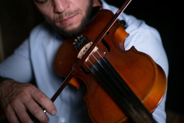 A man plays a violin close-up on a black background