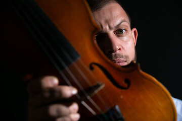 portrait of a violinist on a black background with a violin in his hands