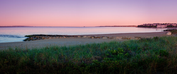 Panoramic beach seascape with pink sky and reflections on Cape Cod at dawn