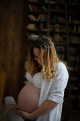happy pregnant woman eighth ninth month of pregnancy hugging her belly with her hand and looks at...