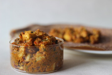 Cottage cheese gravy with tomatto and red chilly. Served in a glass bowl.