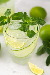 Cold refreshing drinks with lime and cucumber, summer iced beverage and fresh green mint, glass with lemon water close up