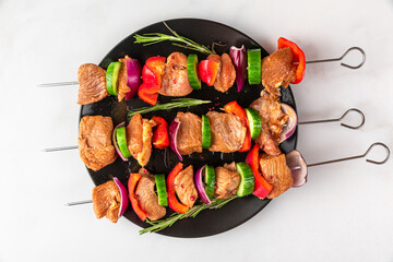 Raw shish kebab. Marinated barbecue meat on skewers with vegetables and spices over white...