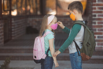 Brother takes care of his little sister and correct the mask on her face at school