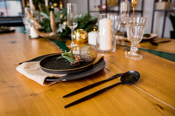 Festive table setting with rustic decorations for Christmas. New Year holidays, celebration, decorations in modern interior design.tableware, eco style,candles with warm fires and conifers brunches