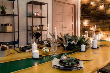 Festive table setting with rustic decorations for Christmas. New Year holidays, celebration, decorations in modern interior design.tableware, eco style,candles with warm fires and conifers brunches