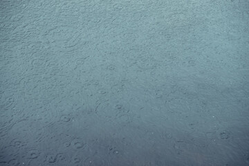 Atmospheric nature background of azure water in mountain lake. Scenic nature backdrop with rain circles on water surface. Beautiful minimalist fragment of blue mountain lake with rainy circles.
