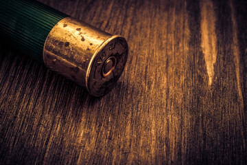 Fototapeta na wymiar One 12 gauge cartridge lying on a wooden table. Close up view