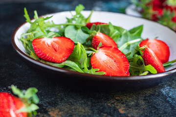 strawberry salad green leaves salad mix arugula, spinach organic on the table healthy food meal snack copy space food background rustic. top view keto or paleo diet veggie vegan or vegetarian food