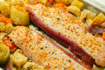 Raw duck breast with vegetables prepared on a metal baking tray