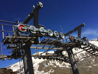 Ski lifts for skiers on the slopes and tops of a mountain, machinery with towers, gears, wheels and...