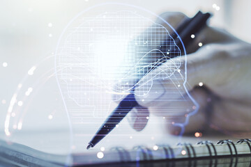 Double exposure of creative artificial Intelligence symbol with man hand writing in notebook on background. Neural networks and machine learning concept