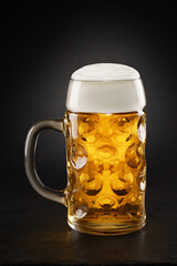 Stein with fresh beer with cap of foam on a black.