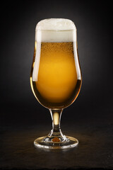Mug with fresh beer with cap of foam on a black.