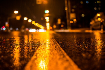 Rainy night in the big city, the glowing lights of approaching cars. View of the level of the dividing line