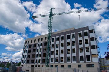 Construcción de un edificio con andamios , grua y cielo azul y nubes blancas de fondo