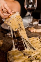 Female Hands Grabs a beautiful Pizza Slice with melted cheese on a wooden table