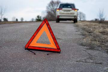 Red emergency stop sign. In the background, the car has stopped and the emergency lights are flashing. Concept of accidents, breakdowns, service services
