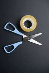 Tijeras de metal y plástico azul con cello sobre cartulina negra