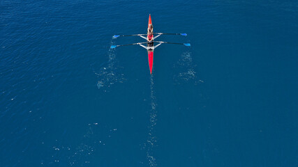 Aerial drone top down photo of sport canoe operated by team of young women in emerald calm sea waters - obrazy, fototapety, plakaty