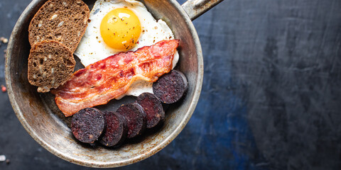 english breakfast fried egg fresh black pudding blood sausage, cereal bread, beans, bacon, scrambled eggs food healthy meal snack copy space food background rustic top view