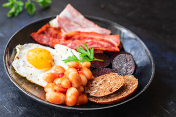 english breakfast fried egg fresh black pudding blood sausage, cereal bread, beans, bacon, scrambled eggs food healthy meal snack copy space food background rustic top view