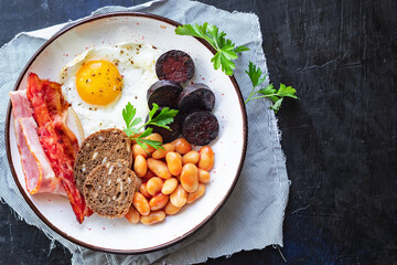 english breakfast fried egg fresh black pudding blood sausage, cereal bread, beans, bacon, scrambled eggs food healthy meal snack copy space food background rustic top view