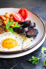 english breakfast fried egg fresh black pudding blood sausage, cereal bread, beans, bacon, scrambled eggs food healthy meal snack copy space food background rustic top view
