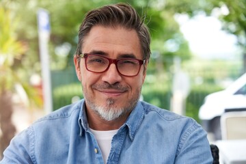 Outdoor portrait of white older man with gray hair, wearing eyewear.