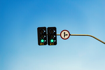 Semáforo com luz verde acesa e sinalização de siga em frente ou vire à direita.