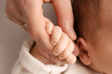A newborn holds on to mom's, dad's finger. Hands of parents and baby close up. A child trusts and holds her tight