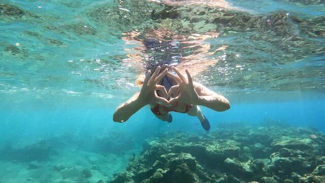 woman in sea on face snorkelling mask show by hands heart big love and declaration of love, after two thumbs up super,. trip into water all underwater world to see fish in vacation