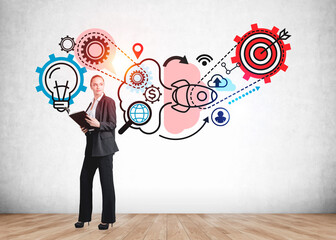 Attractive young businesswoman holding a notebook, standing near drawing with gears, target. Process of thinking icons on concrete wall. Task and goal, concept of human intelligence and plan