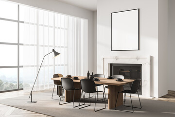 Stylish designed modern interior of dining room with fire pace, table and six black chairs. Minimalist style of home decor. Empty white framed poster on wall.