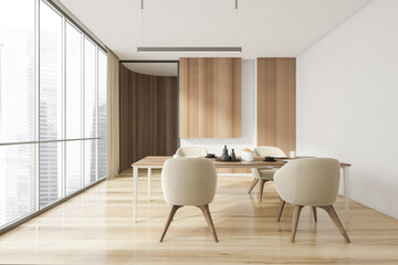 Stylish and wood interior of dining room with design table and four beige chairs. Minimalist style of home decor. Parquet floor. Panoramic window with city view.