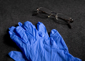 Blue glove and glasses on dark gray background