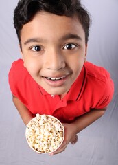  happy little Indian boy eating popcorn 